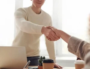 A job offer is agreed and the new employ shake hands with his interviewer